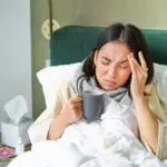 Flu, sickness and people. Young woman feeling sick, having fever and catching col, lying in bed